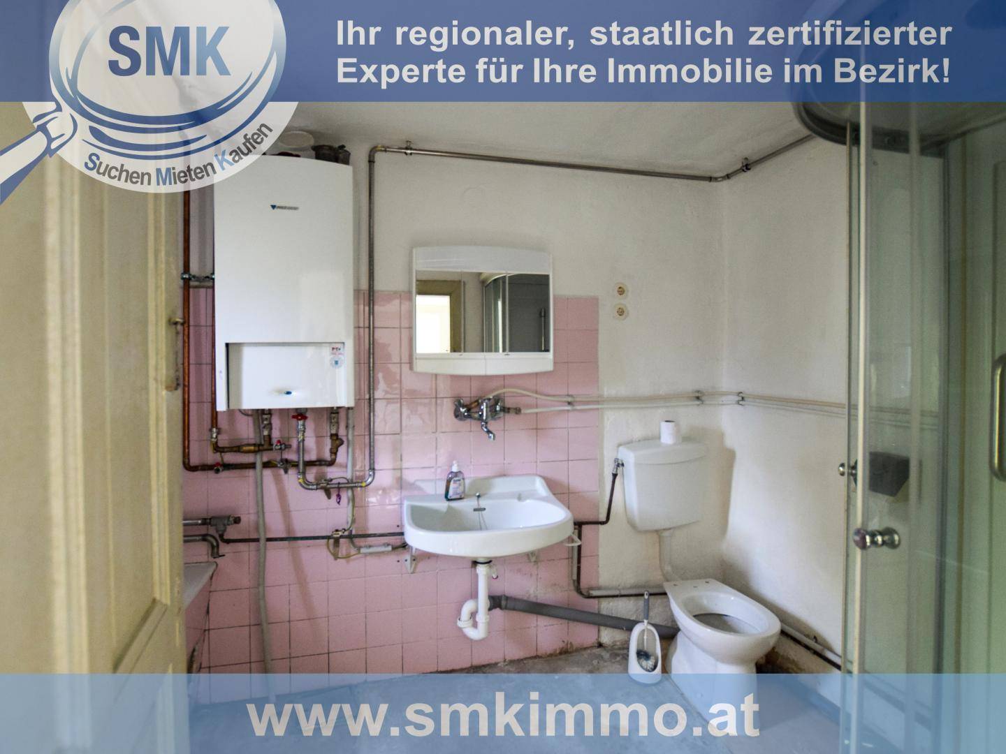 Badezimmer mit rosa Fliesen, Waschbecken, Toilette, Dusche und sichtbaren Leitungen.