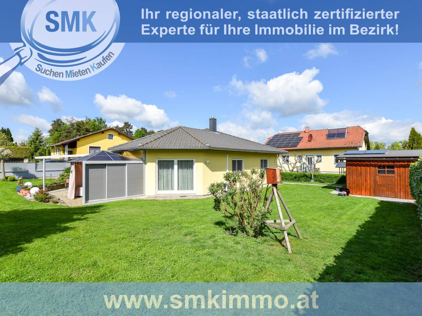Ansicht des Hauses von hinten mit großem Garten, Rasenfläche und Spielgeräten.