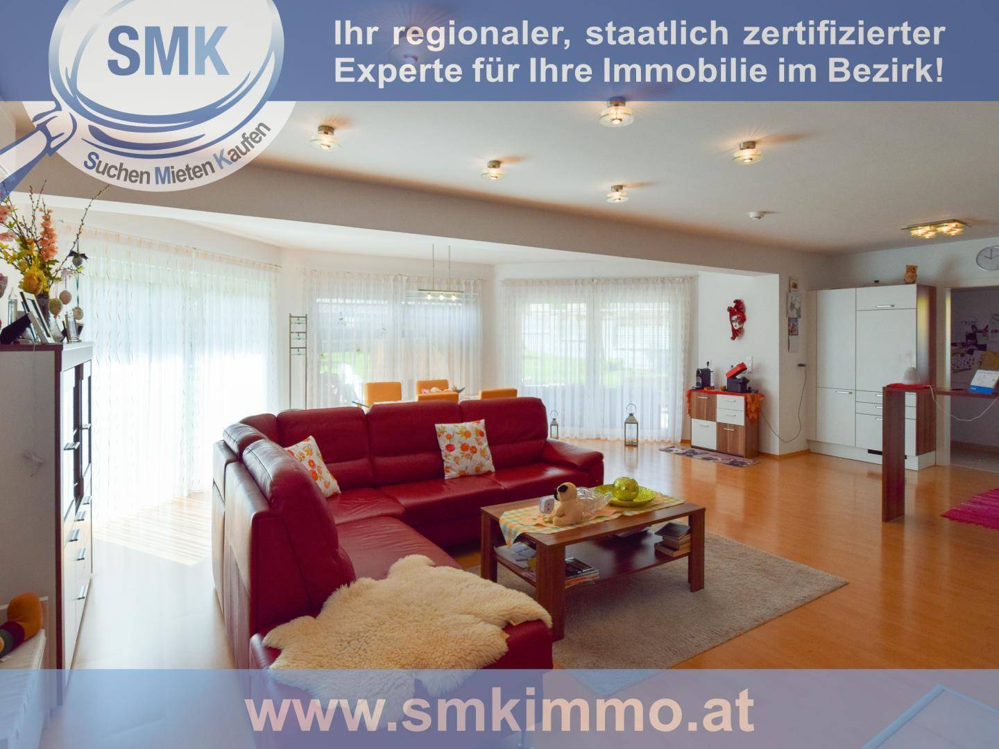 Geräumiger Wohn-Essbereich mit rotem Ecksofa, großen Fenstern und Zugang zum Garten.