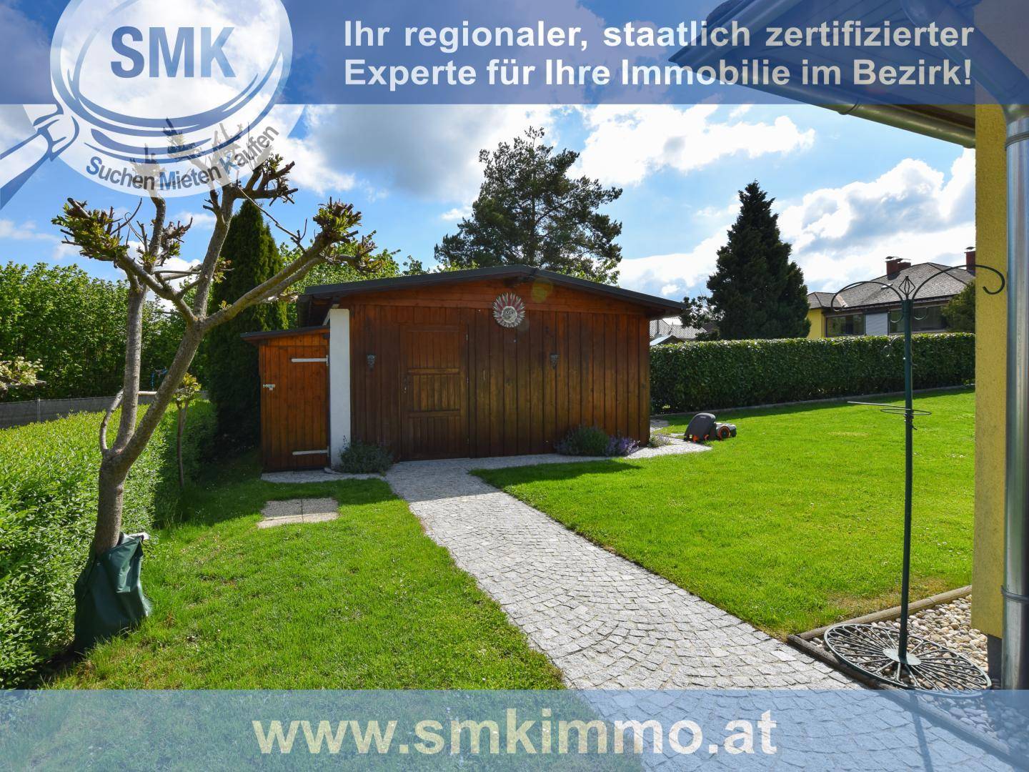 Gepflegter Garten mit Rasenfläche, Gartenweg und einem Holzschuppen im Hintergrund.