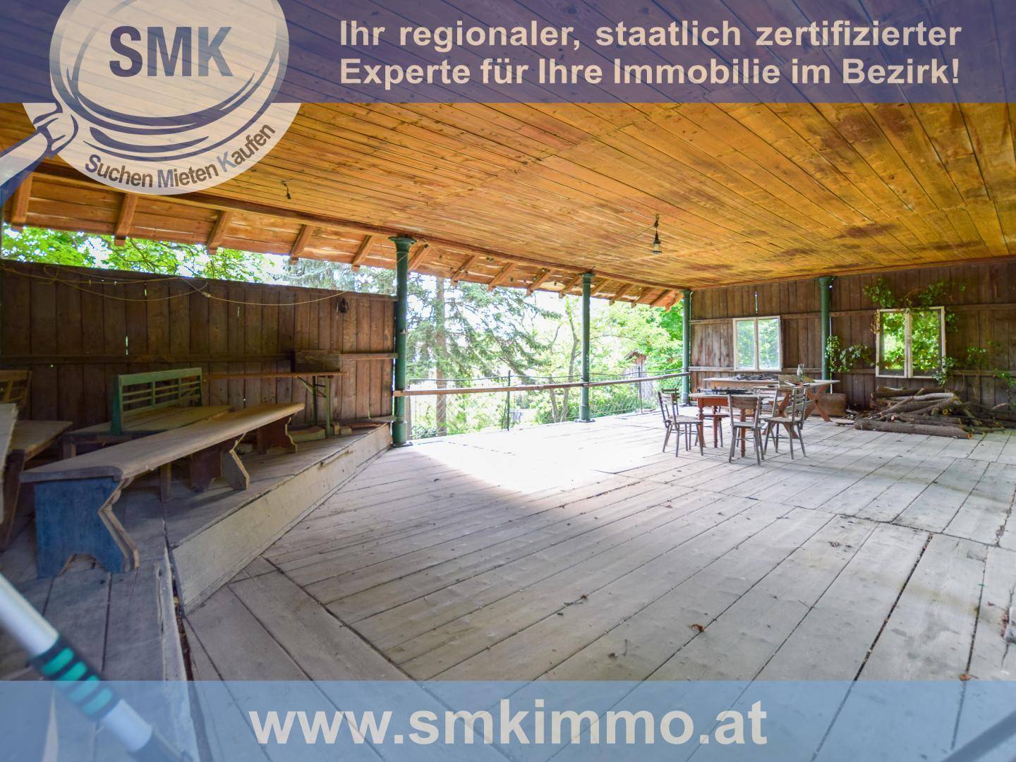 Geräumige überdachte Holzterrasse mit Sitzgelegenheiten und Blick ins Grüne.