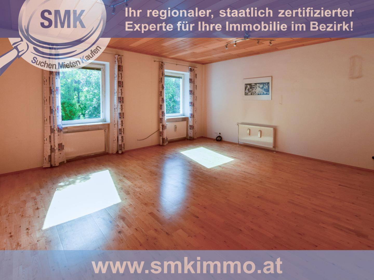 Helles Zimmer mit Holzdielenboden und zwei Fenstern, die viel Tageslicht hereinlassen.