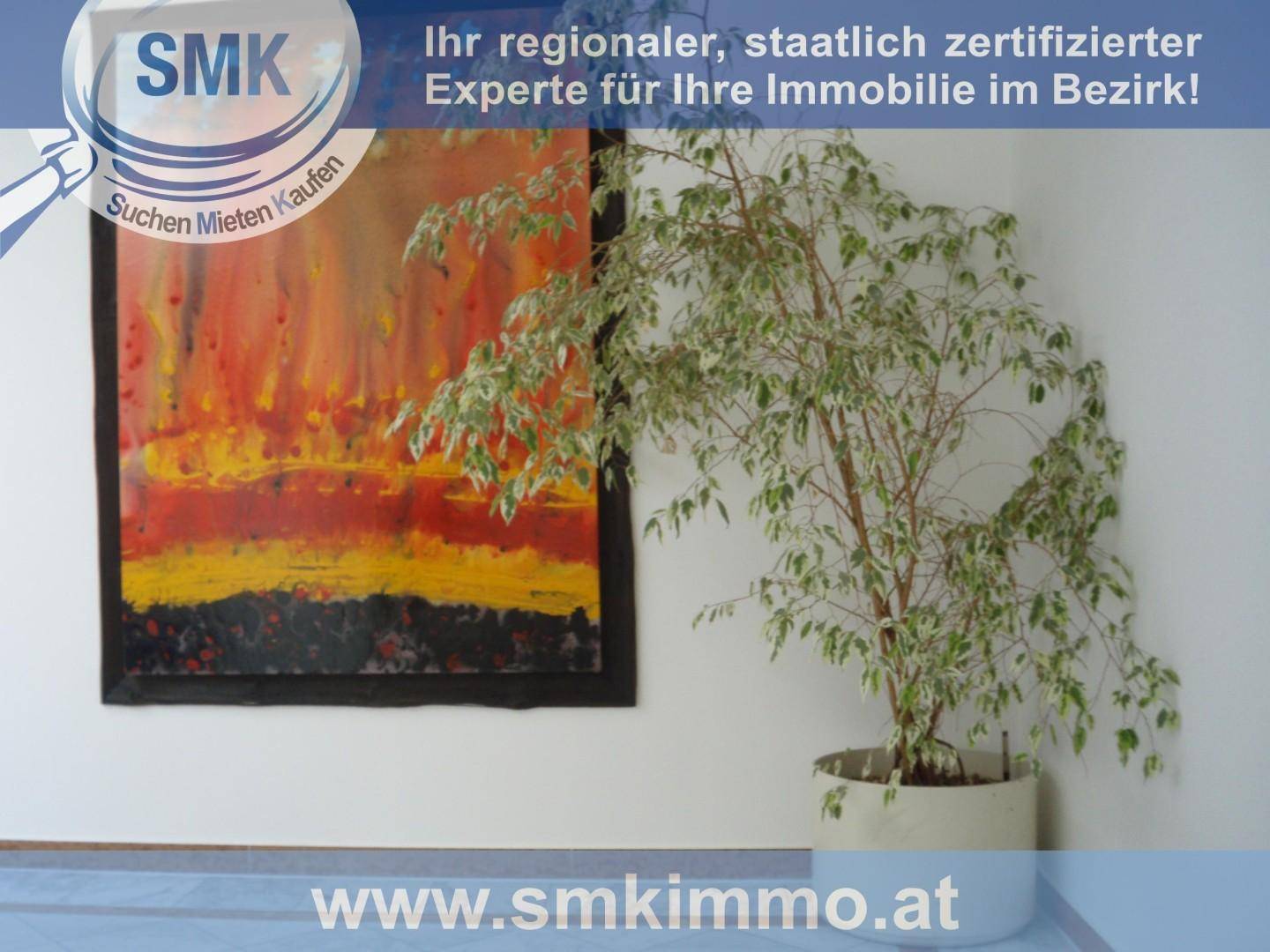 Große Topfpflanze neben einem farbenfrohen, abstrakten Gemälde an einer weißen Wand.