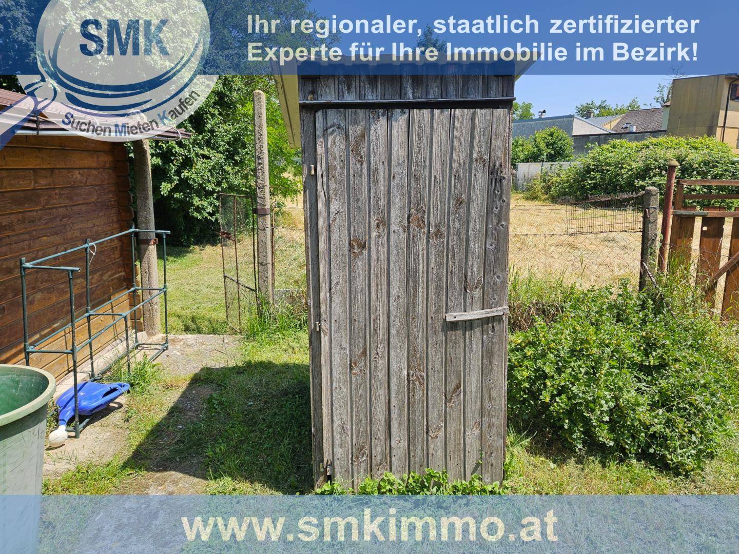 Schmaler Holzschuppen oder Außentoilette in einem grünen Gartenbereich.