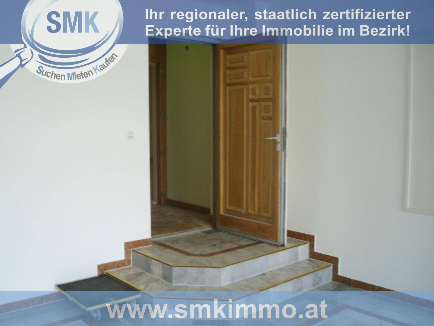 Eingangsbereich mit Holztür, gefliesten Stufen und hellem Marmorboden in einem Gebäude.