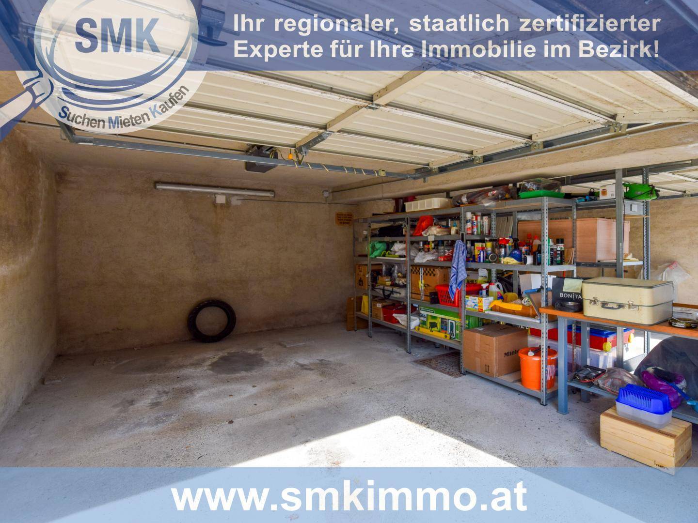 Geräumige Garage mit Betonboden und praktischen Regalsystemen für Lagerung.