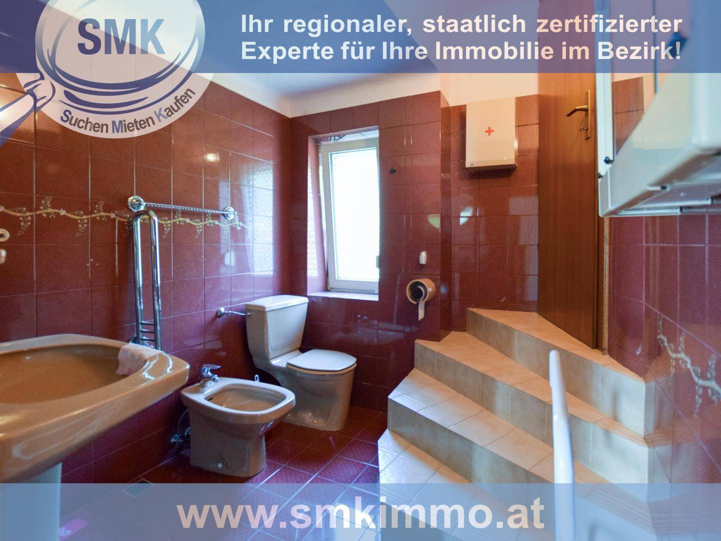 Badezimmer mit roten Fliesen, Toilette, Bidet und Waschbecken, mit Stufen zum Ausgang.