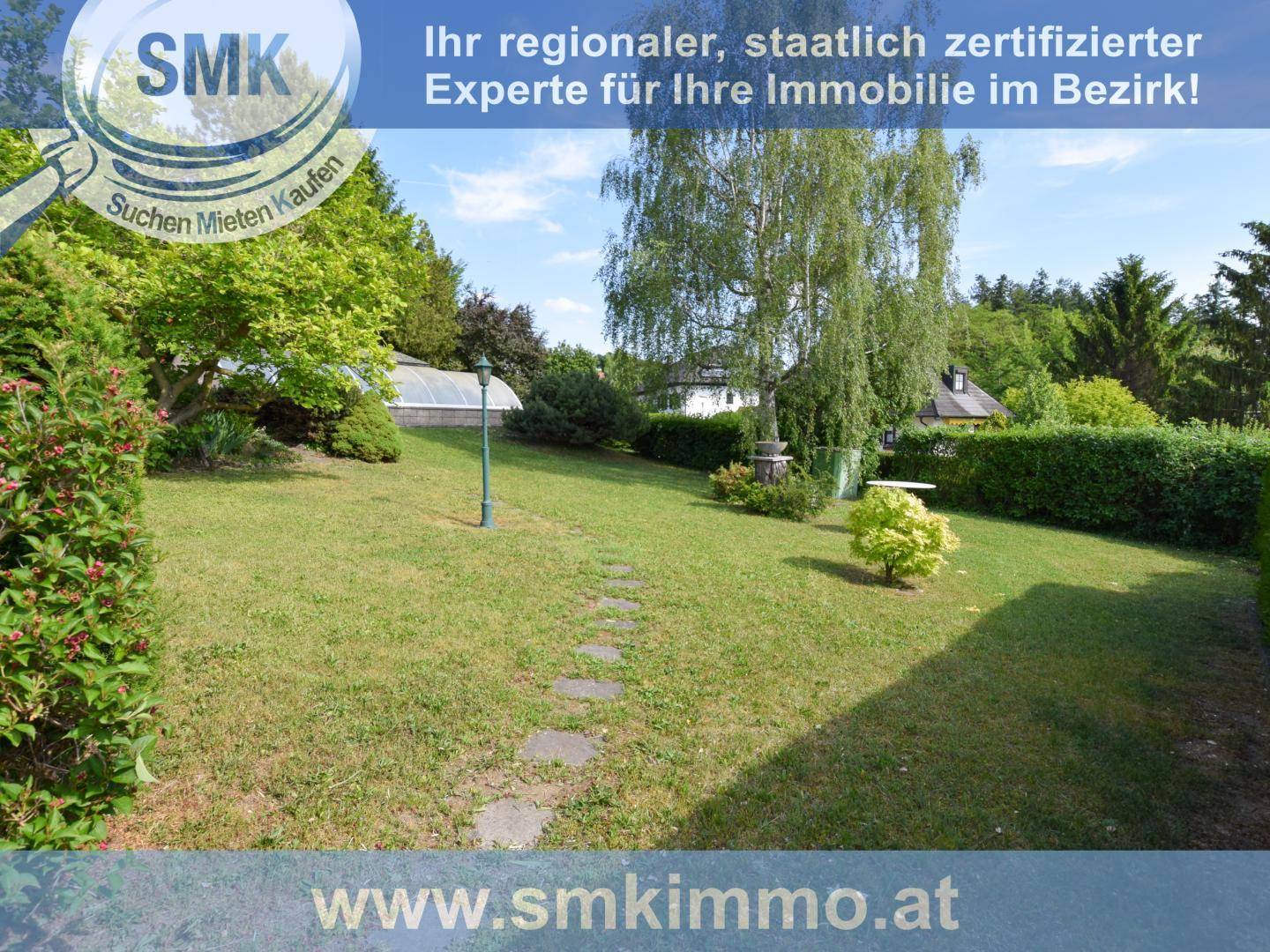 Grüner Garten mit Rasenfläche, Bäumen und einem Steinweg, der durch das Gelände führt.