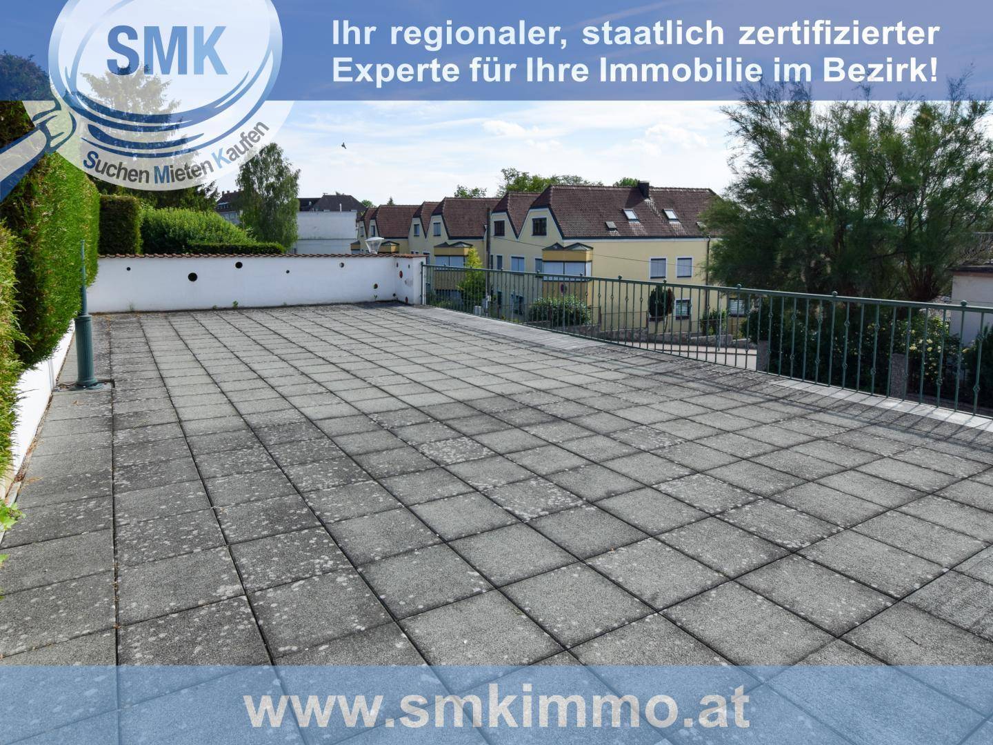 Große gepflasterte Terrasse mit Metallgeländer und Blick auf die umliegenden Häuser.