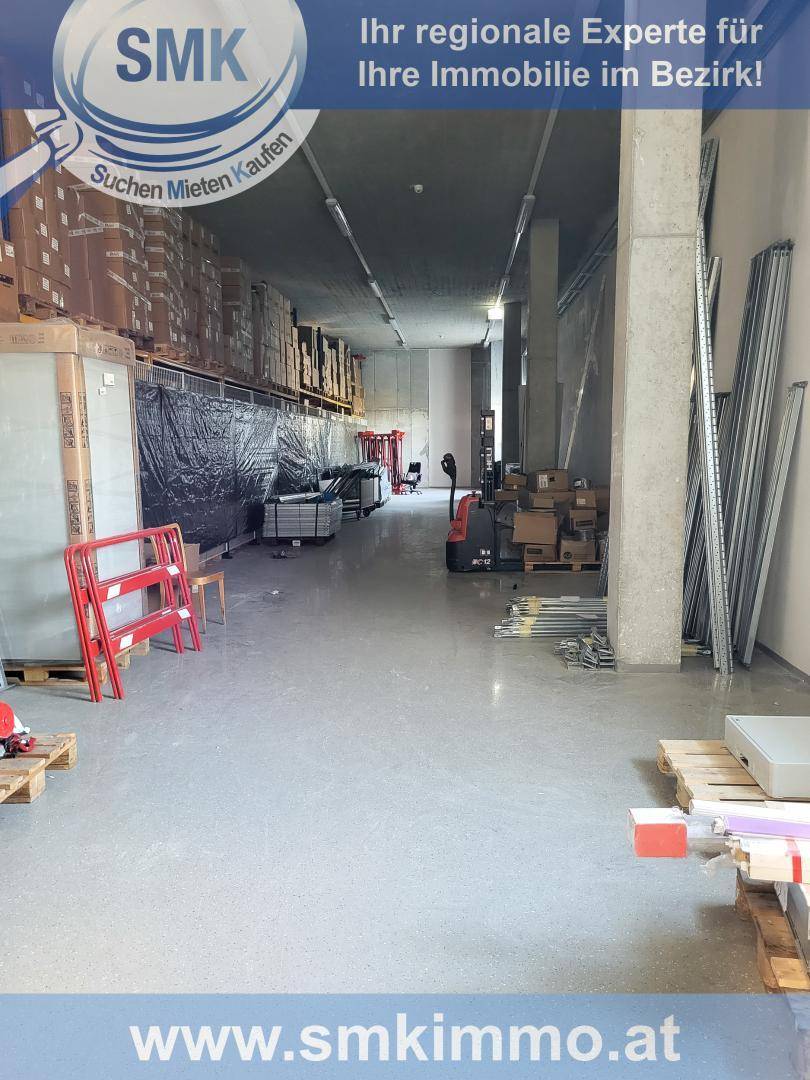 Lagerhalle mit gestapelten Waren, Paletten und einem Gabelstapler auf dem Betonboden.