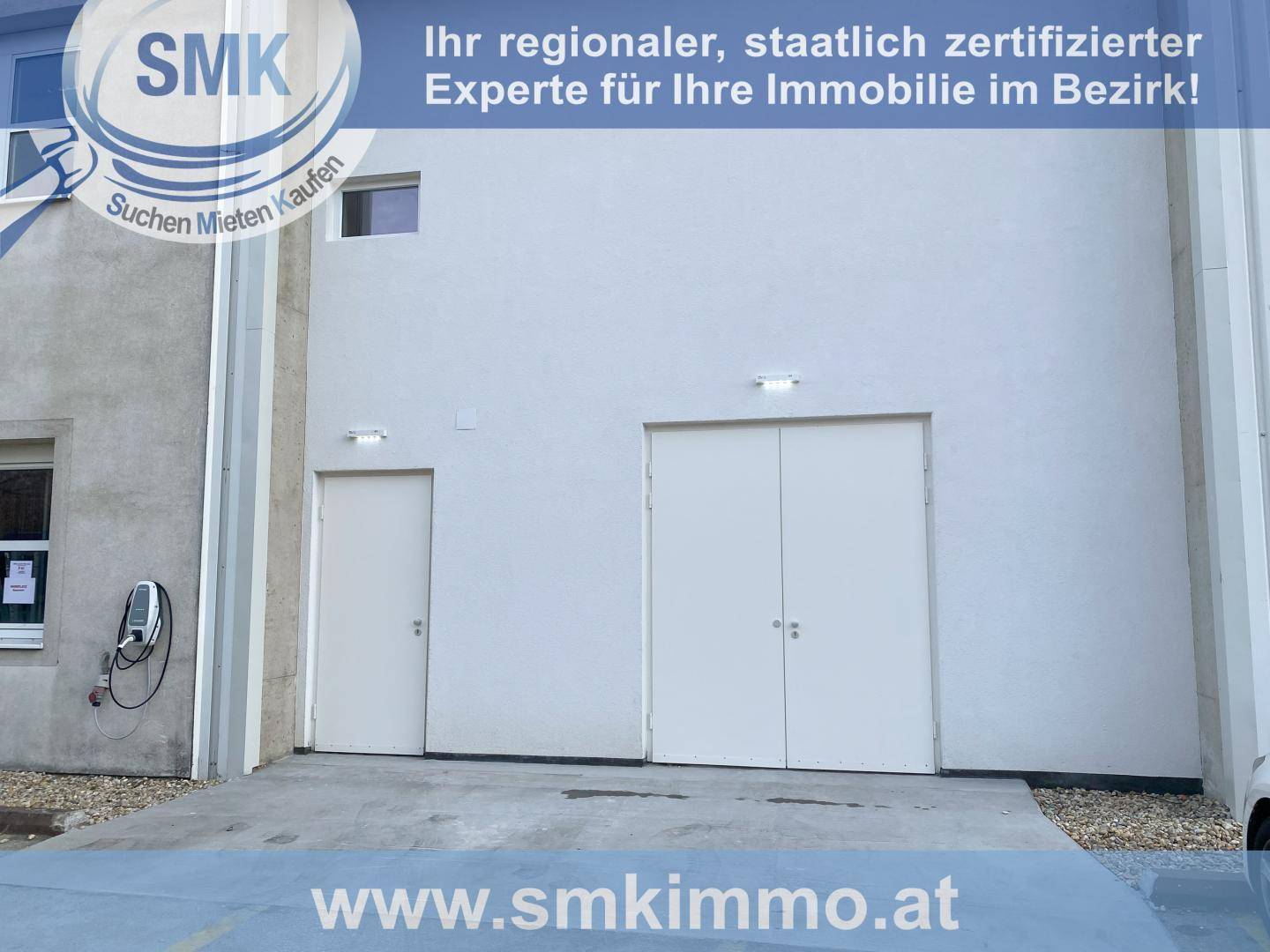 Außenansicht eines Gebäudes mit zwei Eingängen und einer Ladestation für Elektrofahrzeuge.