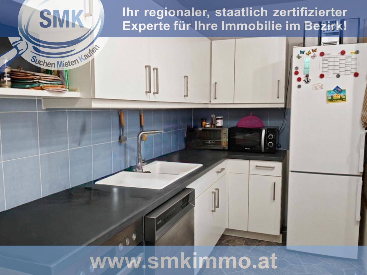 Küche mit weißen Oberschränken, blauer Fliesenrückwand, Spüle, Geschirrspüler und Kühlschrank.