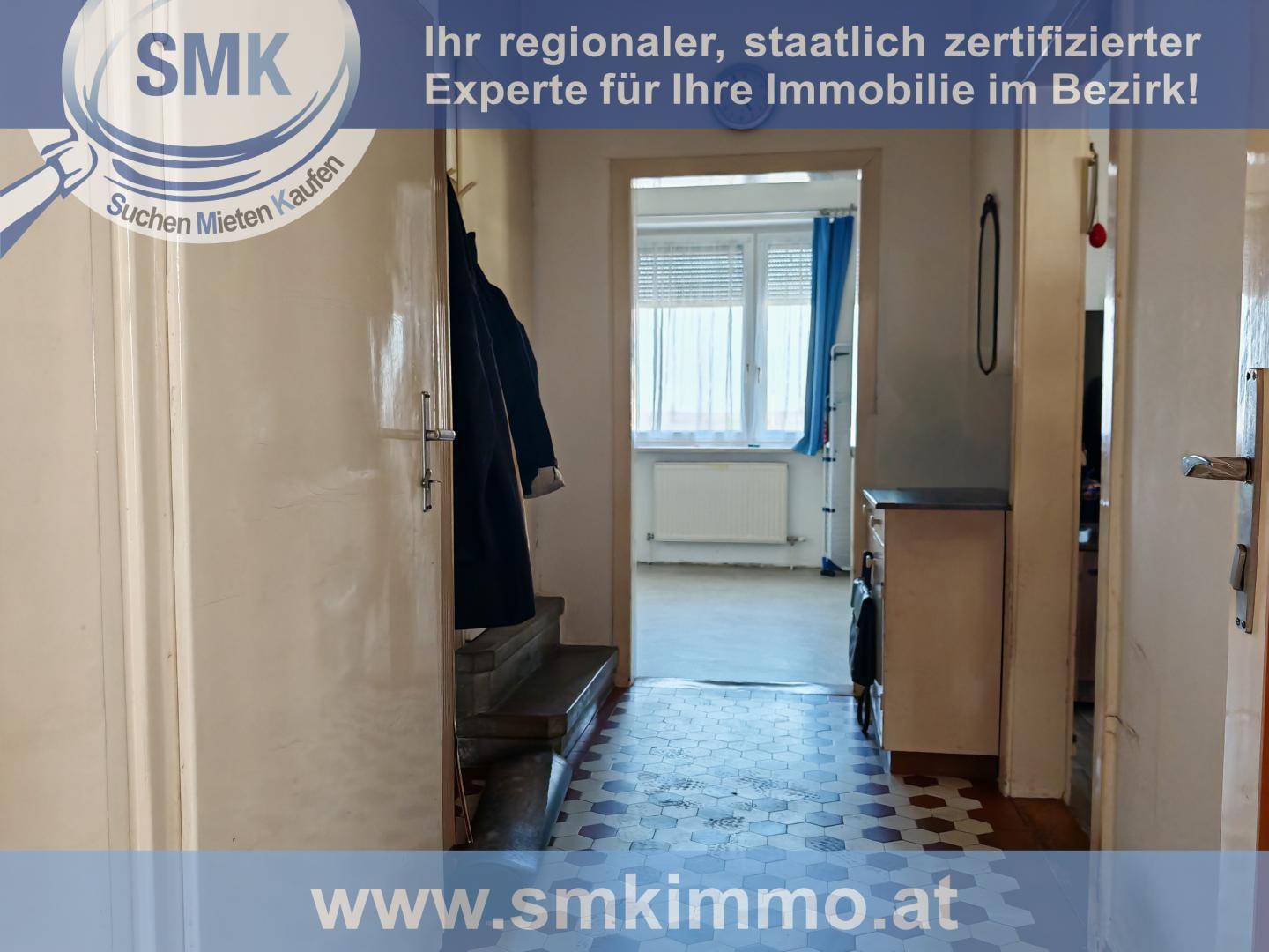 Flur mit Treppe, gemustertem Boden und Blick auf ein Fenster im hinteren Bereich.