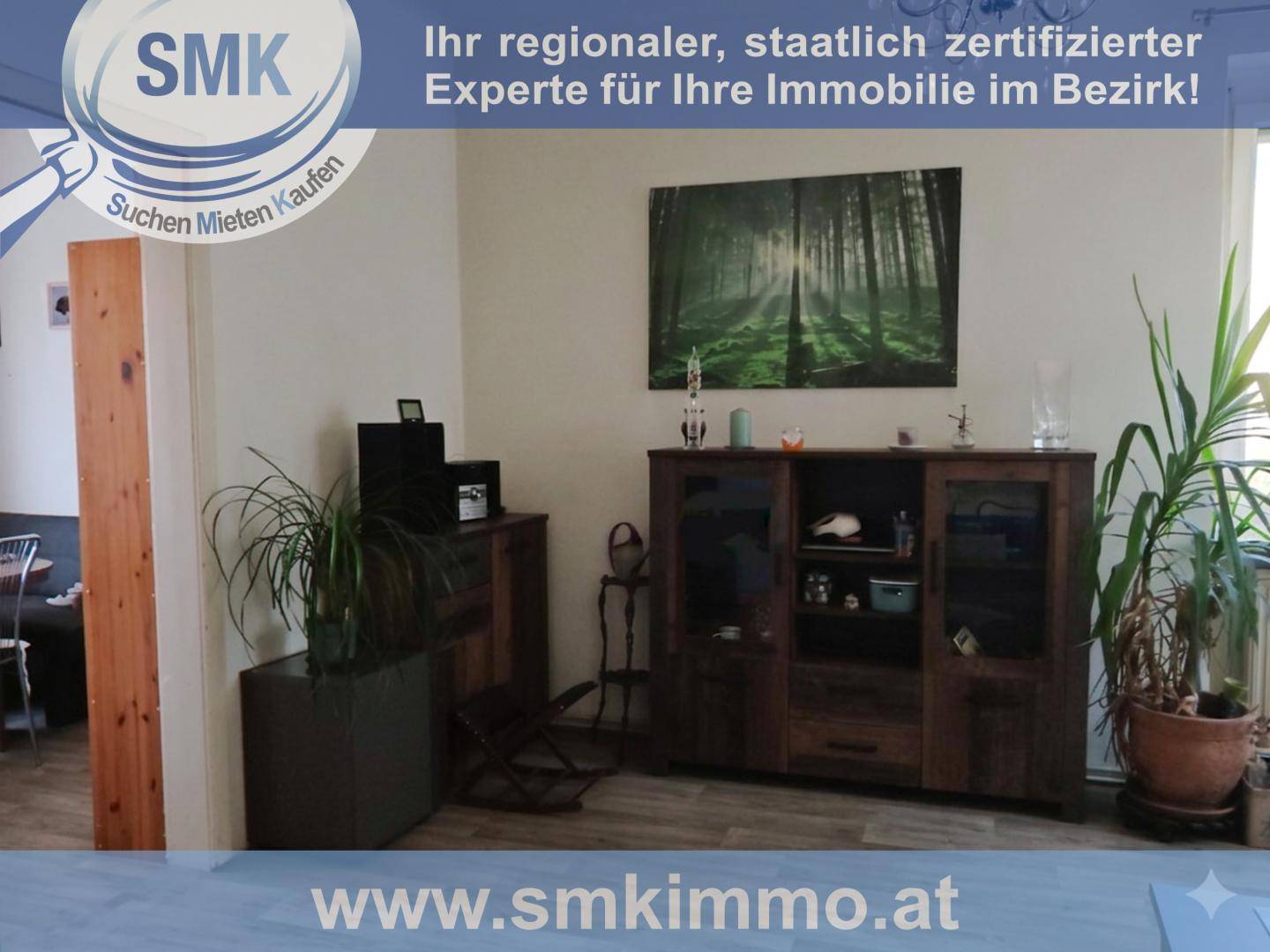 Wohnbereich mit dunklen Holzmöbeln, Pflanzen und einem großen Wandbild.