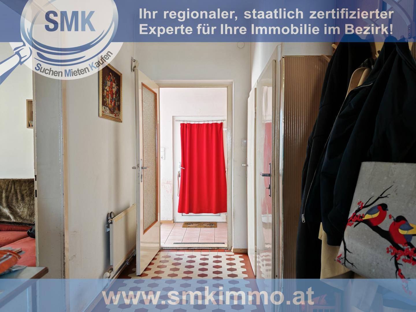 Flur oder Eingangsbereich mit gemustertem Boden, Garderobe und einem roten Vorhang im Hintergrund.