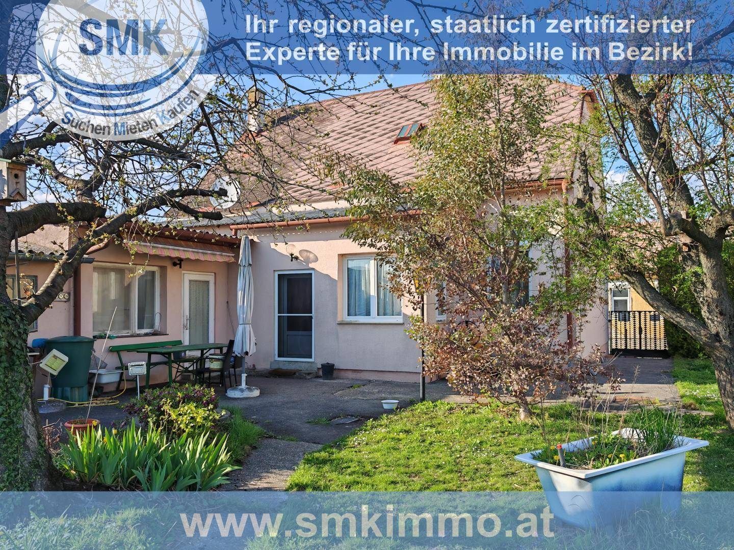 Hinterhof des Hauses mit kleiner Terrasse, Gartenmöbeln und einem ungepflegten Gartenbereich.
