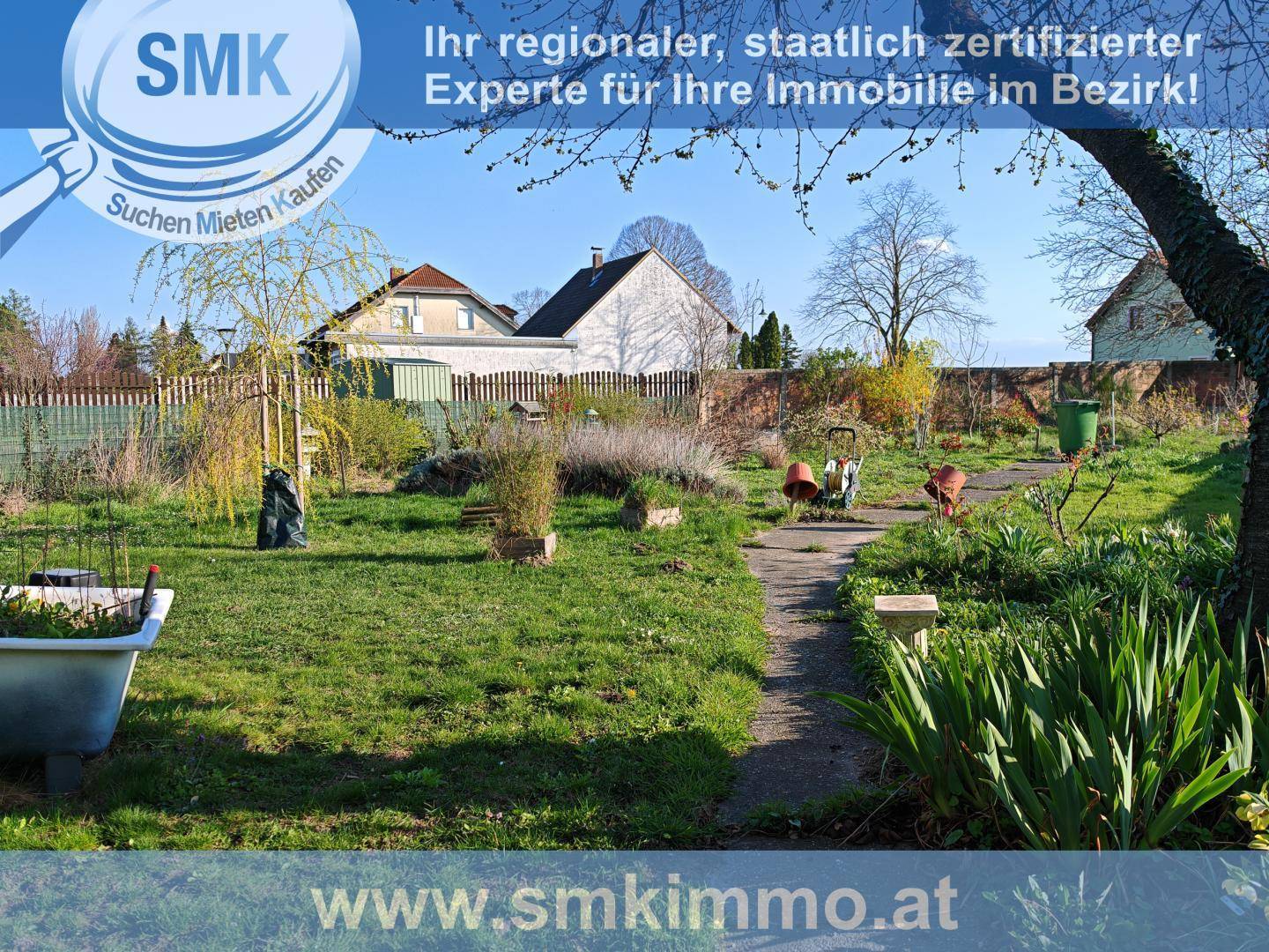 Blick in den weitläufigen Gartenbereich des Anwesens mit Rasenfläche und Pflanzen.