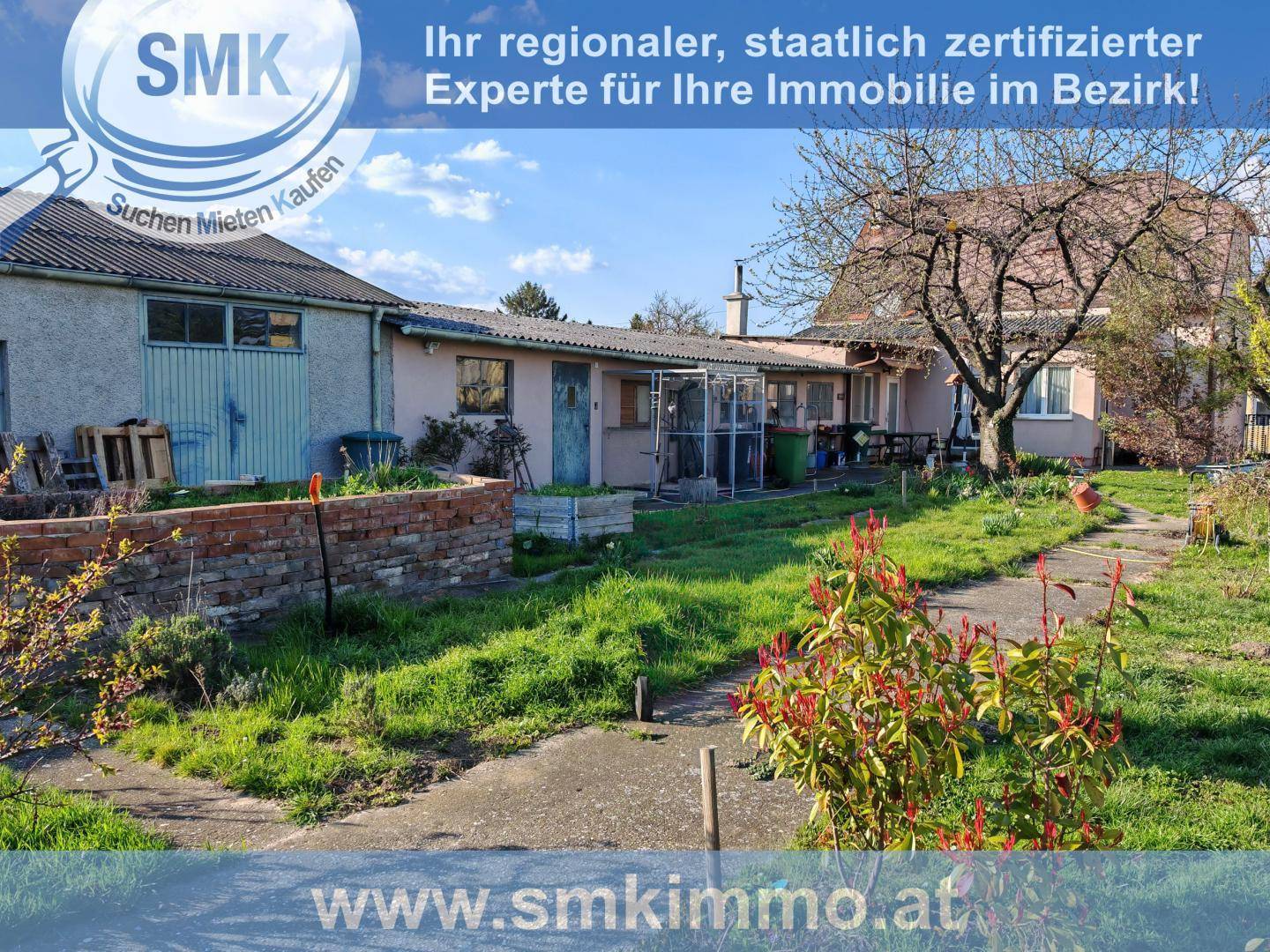 Weitläufiger Gartenbereich mit Rasenflächen, Wegen und verschiedenen Nebengebäuden im Hintergrund.
