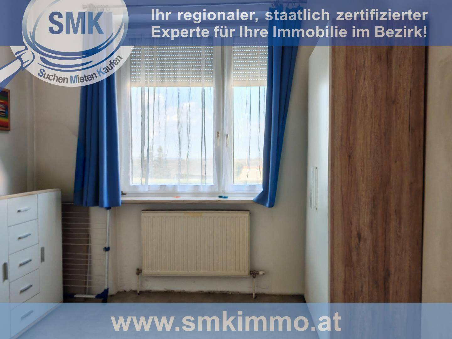 Schlafzimmer mit großem Fenster, Heizkörper und einem Kleiderschrank.