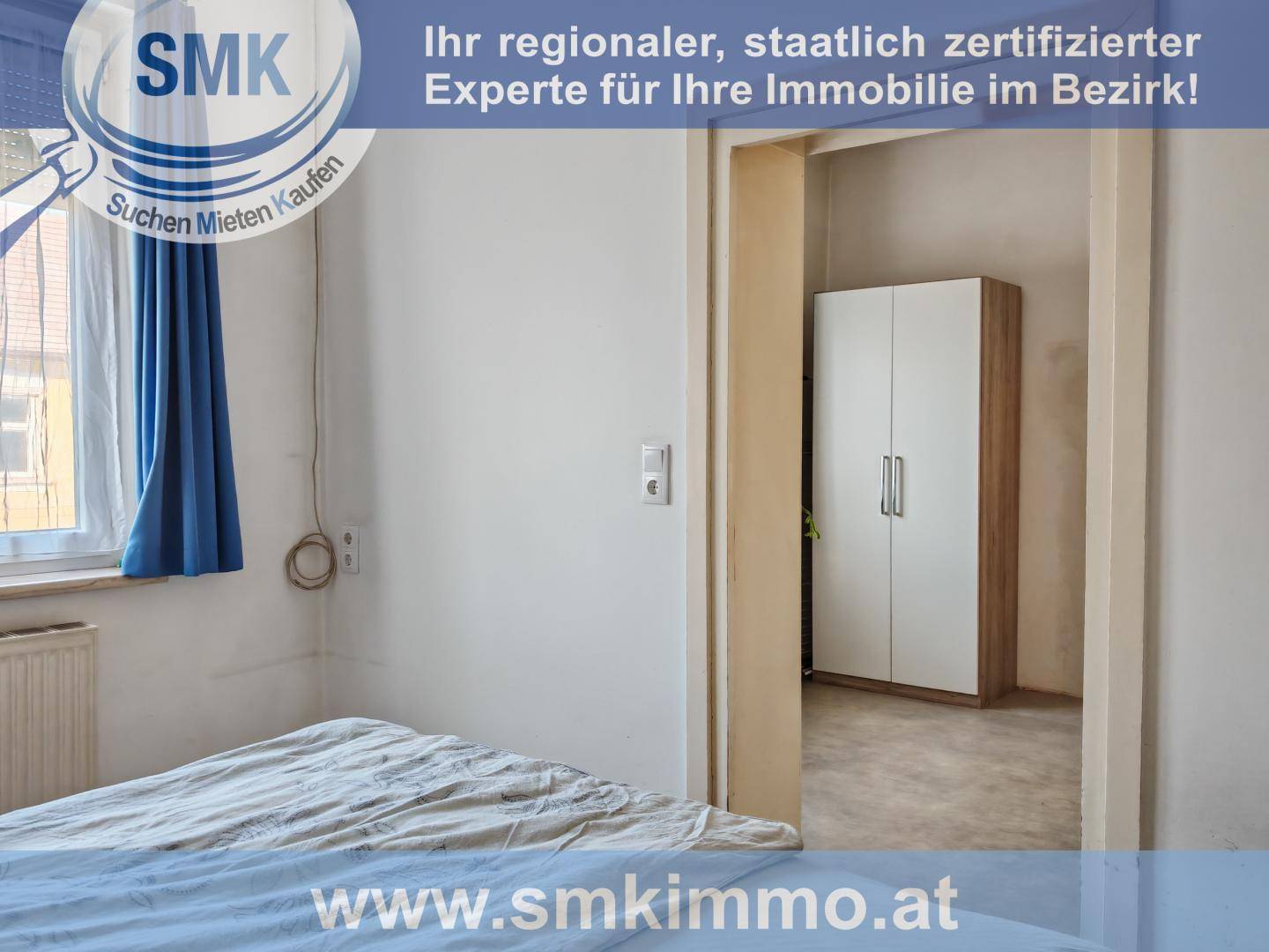 Schlafzimmer mit Bett und Blick durch eine offene Tür auf einen weiteren Raum mit Kleiderschrank.