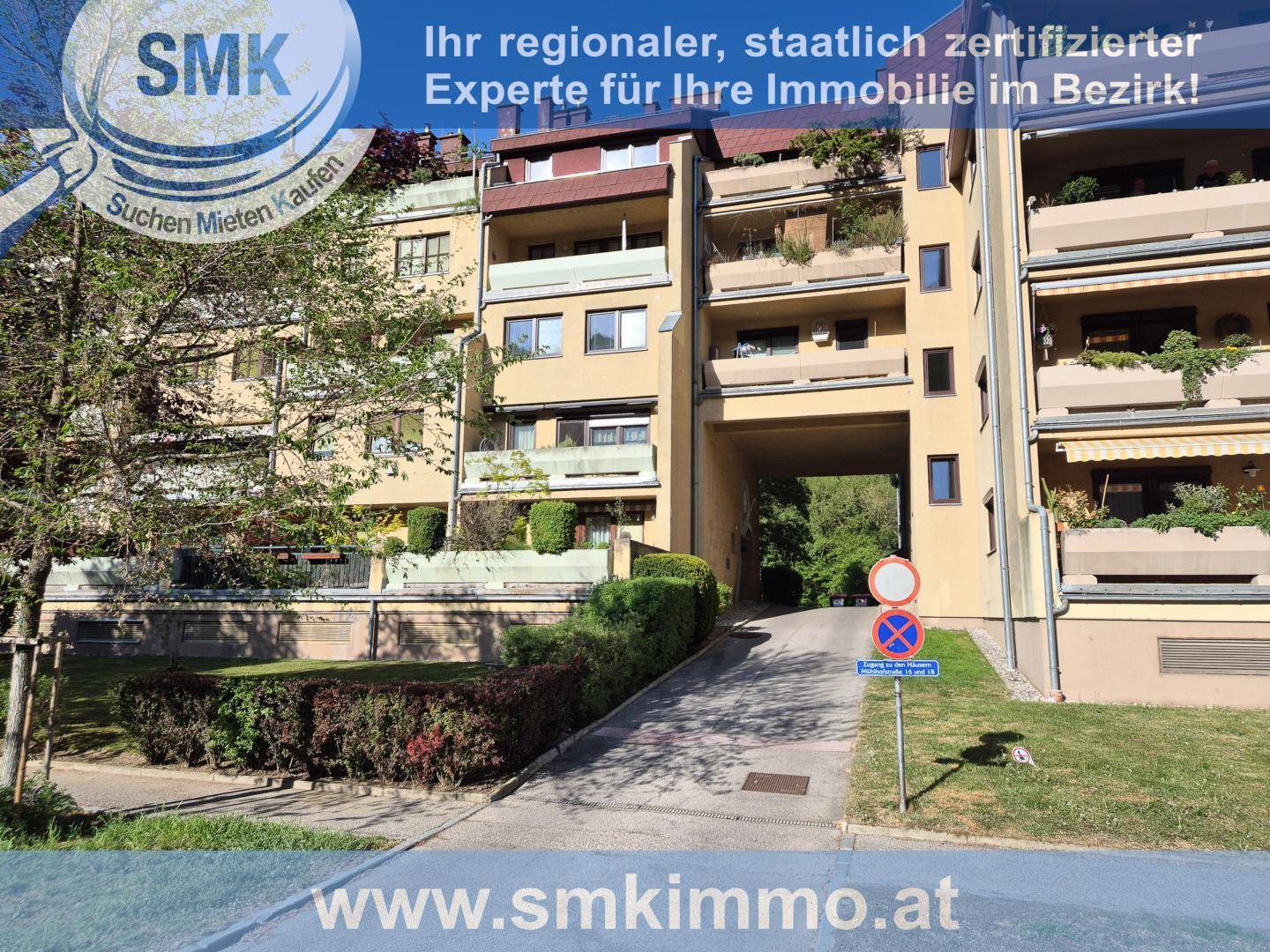 Mehrfamilienhaus mit vielen Balkonen und begrünten Außenanlagen in städtischer Umgebung.