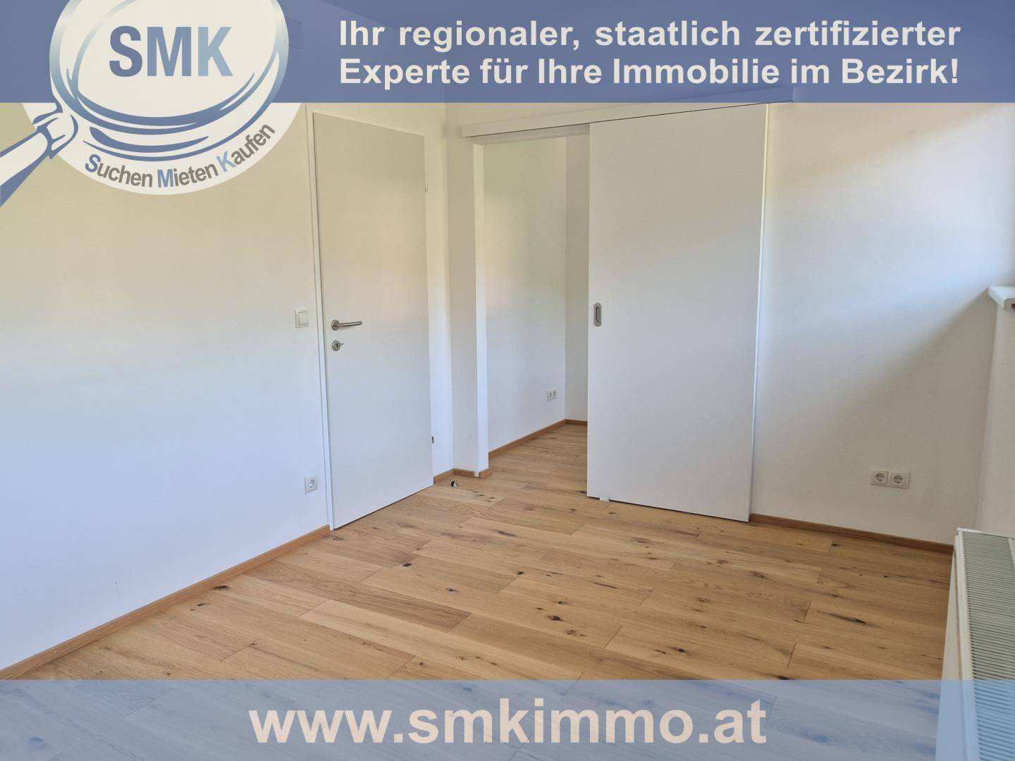 Heller Raum mit Holzboden und weißen Türen, darunter eine moderne Schiebetür.