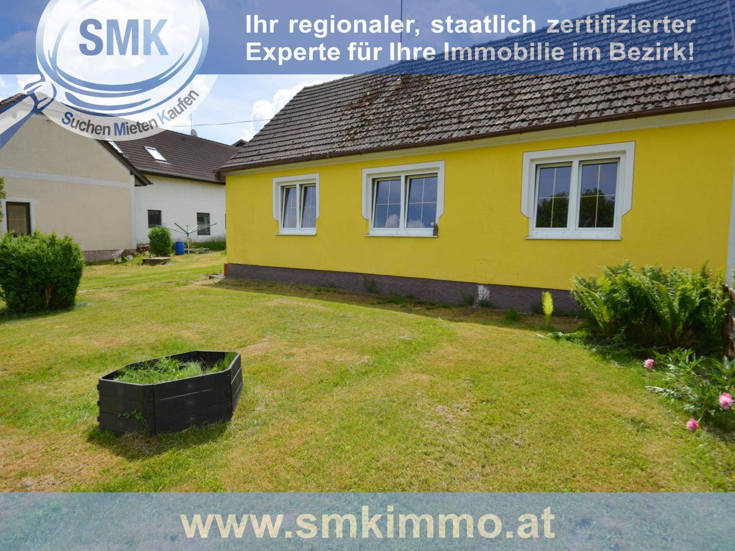 Seitenansicht eines gelben Hauses mit mehreren Fenstern und gepflegtem Rasenbereich.