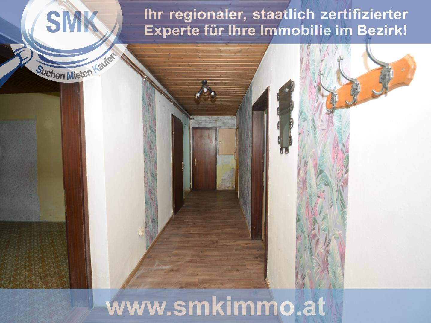 Langer Flur mit Holzdecke, gemusterter Tapete und mehreren Holztüren, die zu Zimmern führen.