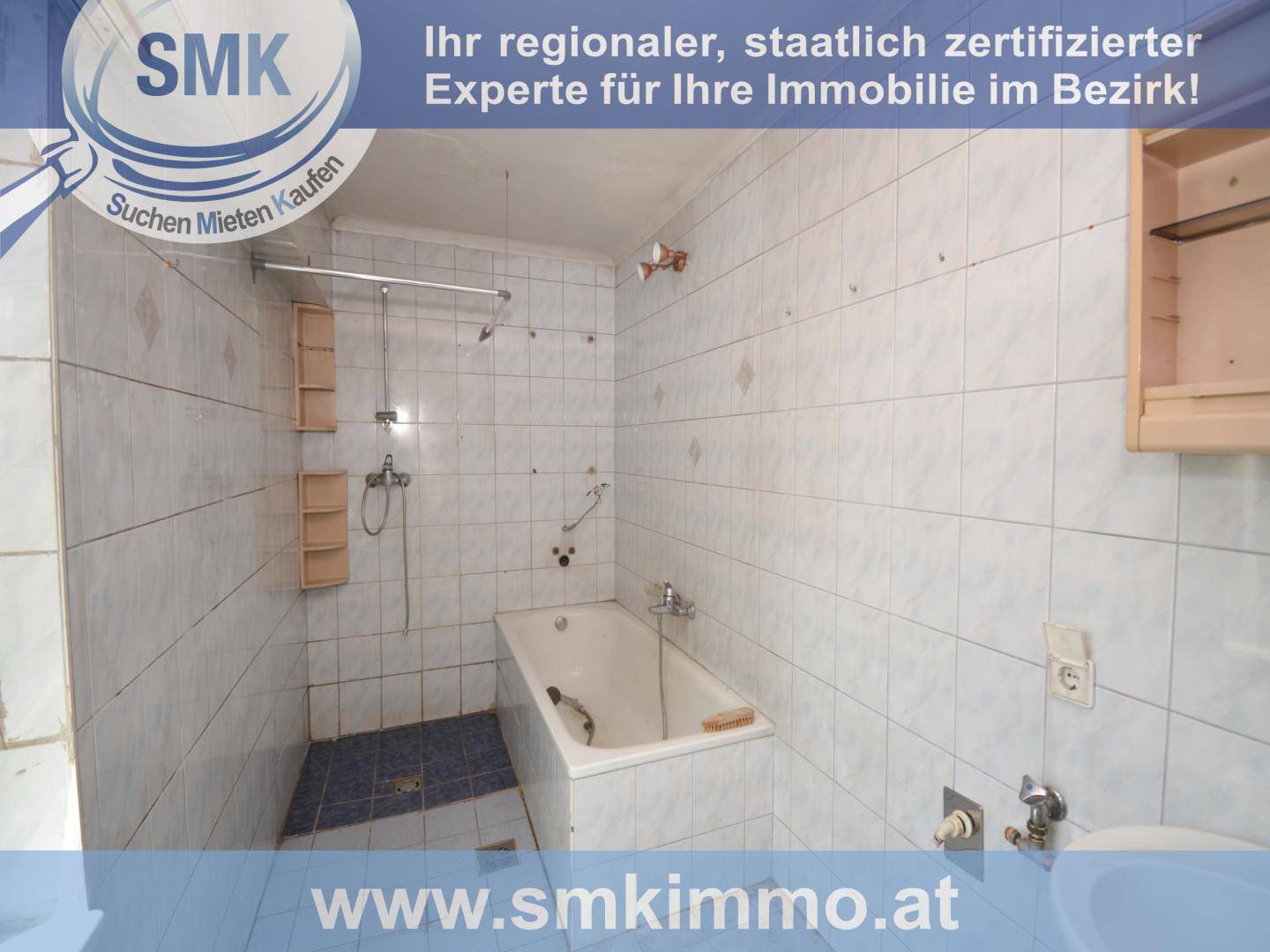 Badezimmer mit hellblauen Fliesen, einer Badewanne und einer Duschstange, in einfachem Zustand.