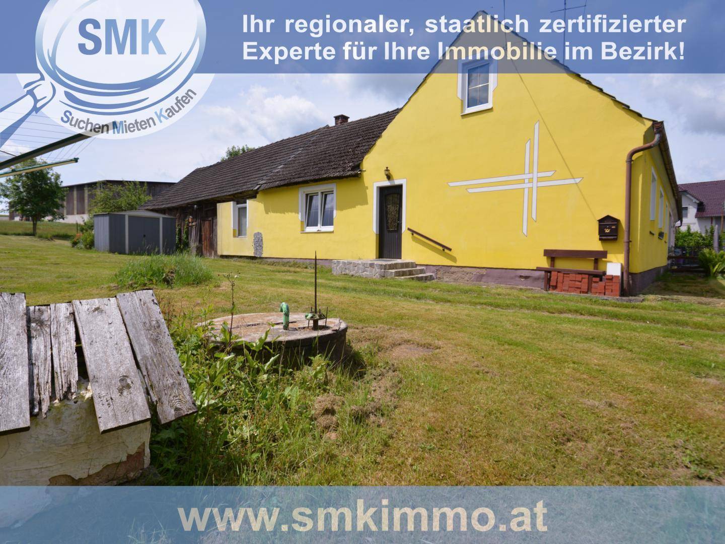 Gelbes Haus mit einem alten Brunnen im Vorgarten und weitem Blick über die grüne Landschaft.