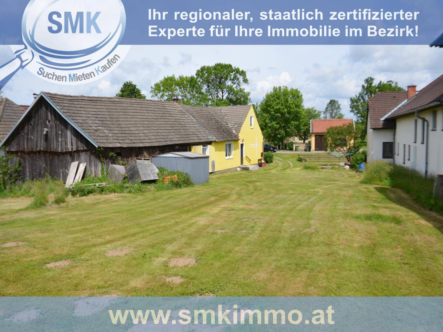 Weitläufiger Gartenbereich mit gelbem Wohnhaus und einem rustikalen Holzgebäude im ländlichen Stil.