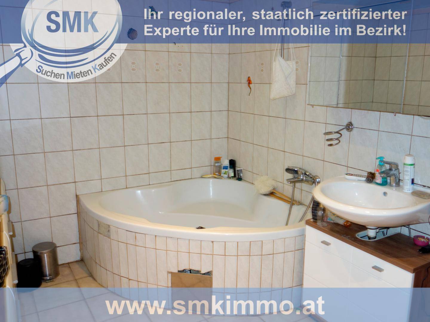 Badezimmer mit Eckbadewanne, Fliesenwänden und Waschbecken, funktional und hell.