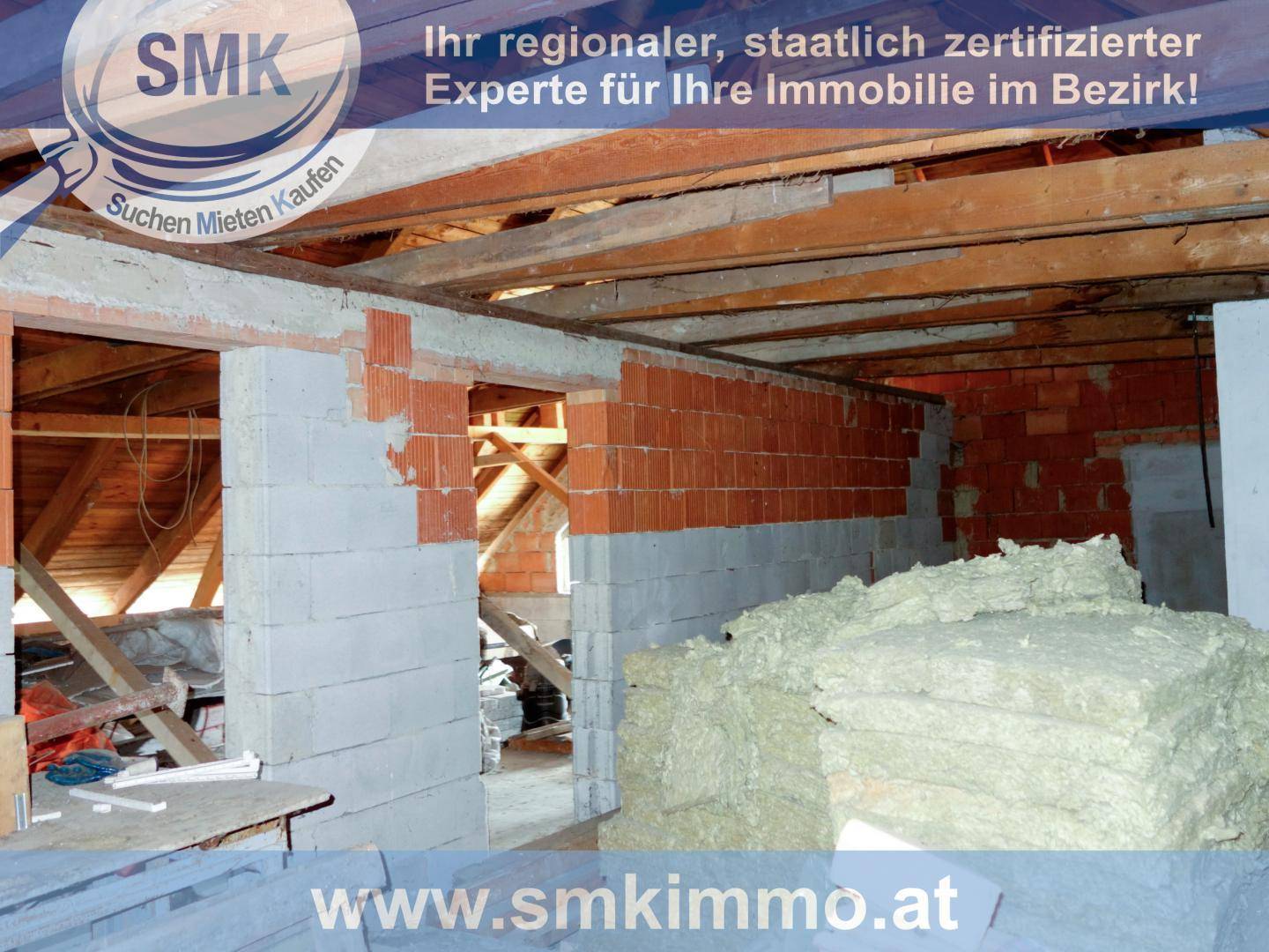 Dachgeschoss im Rohbau mit sichtbaren Holzbalken und Ziegelwänden, bereit für den Ausbau.