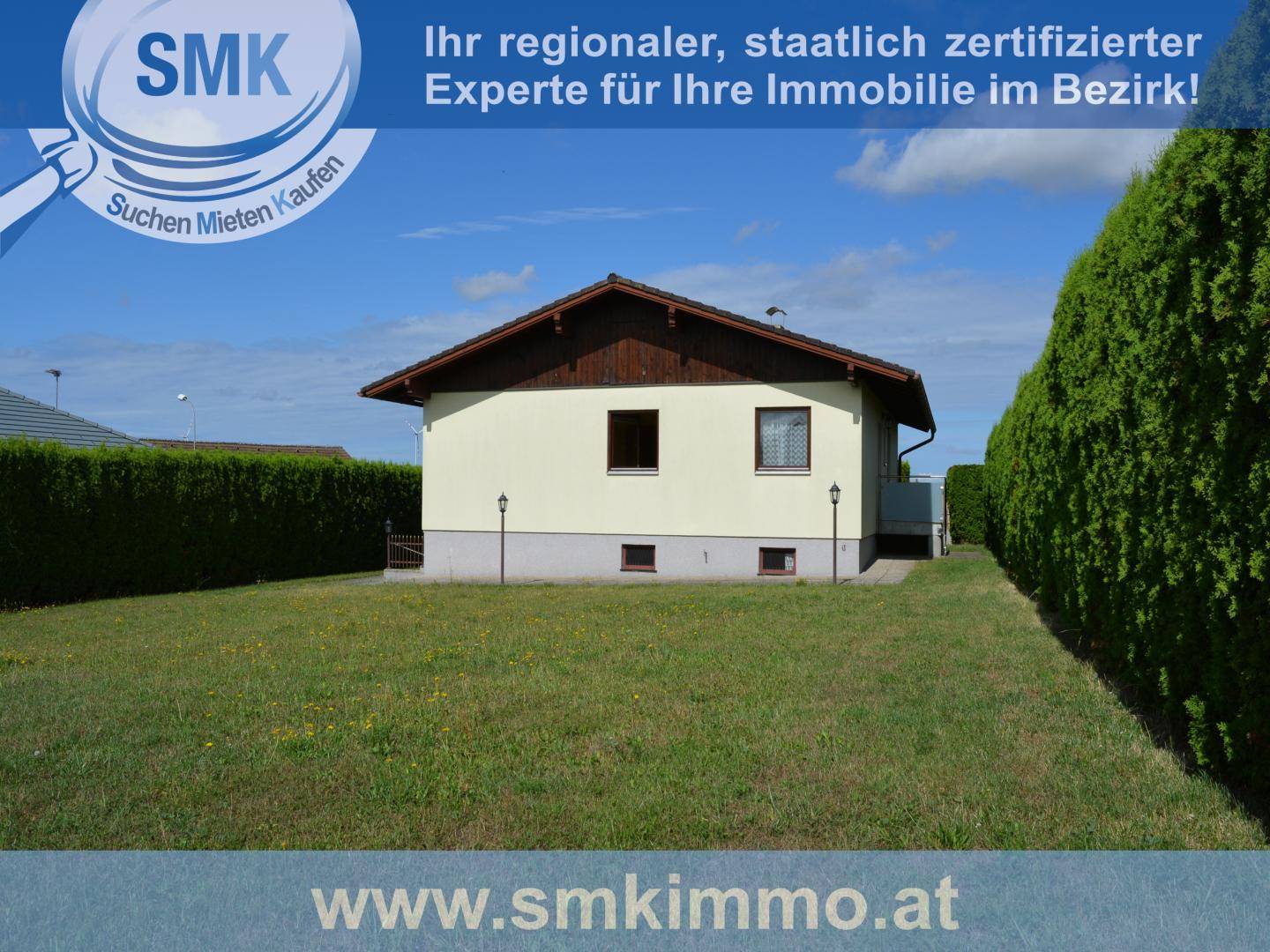 Gesamtansicht des Hauses von der Seite mit großer Rasenfläche und umlaufenden hohen Hecken.
