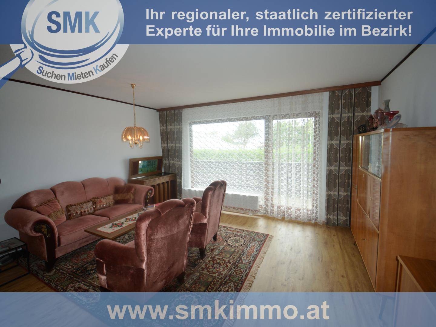 Wohnzimmer mit Sofa, Sesseln, Holzboden und Zugang zu einem Balkon.