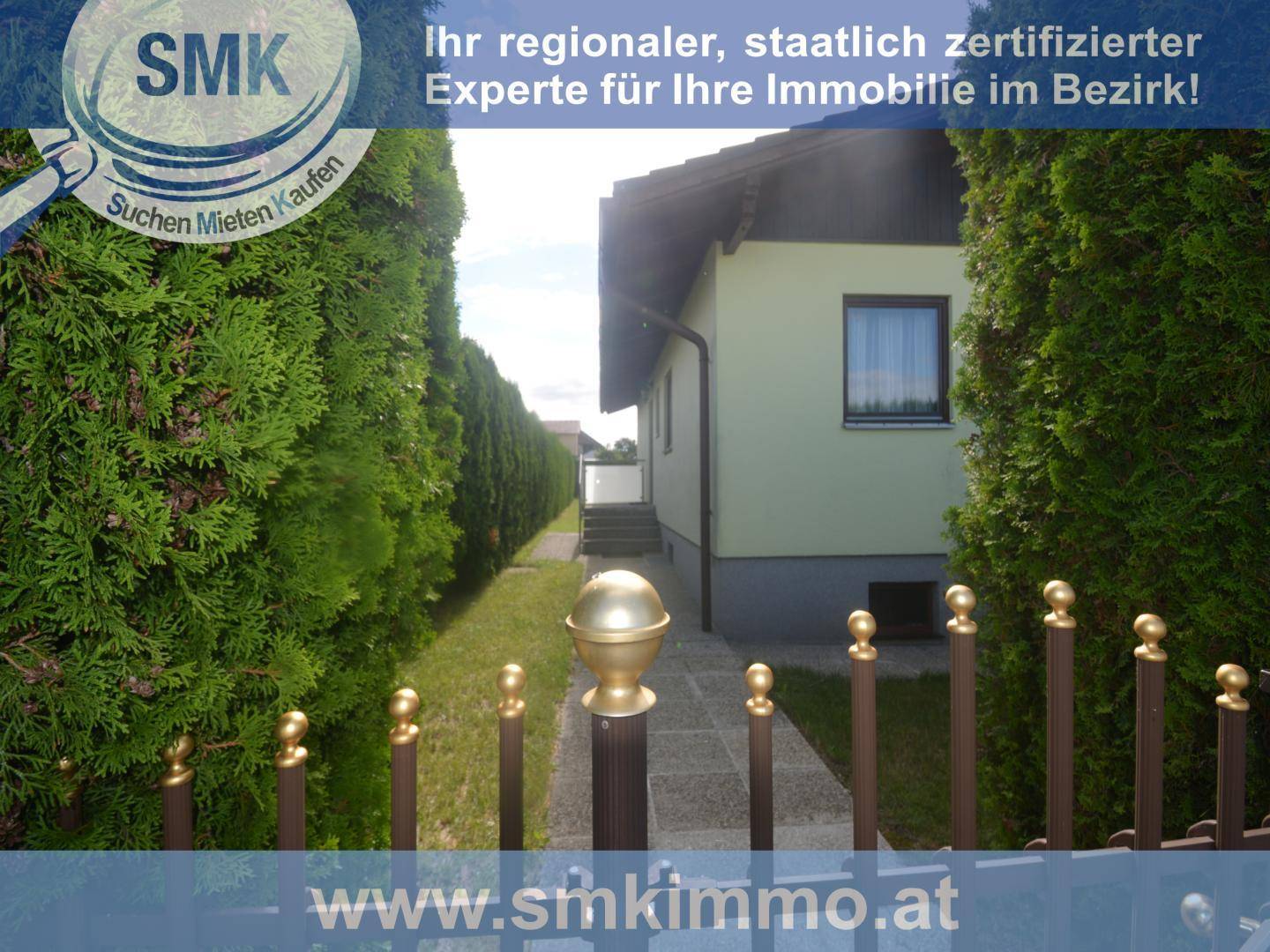 Seitenansicht eines Hauses mit gepflegter Hecke und einem kleinen Gartentor.