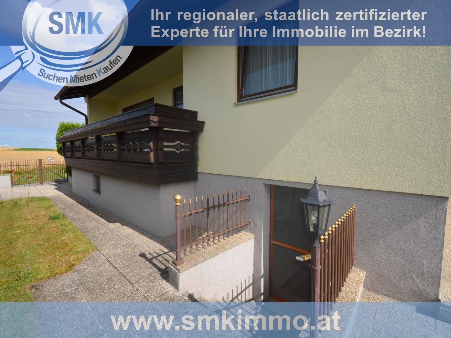Seitenansicht eines Hauses mit Balkon und einem Eingang zum Untergeschoss.