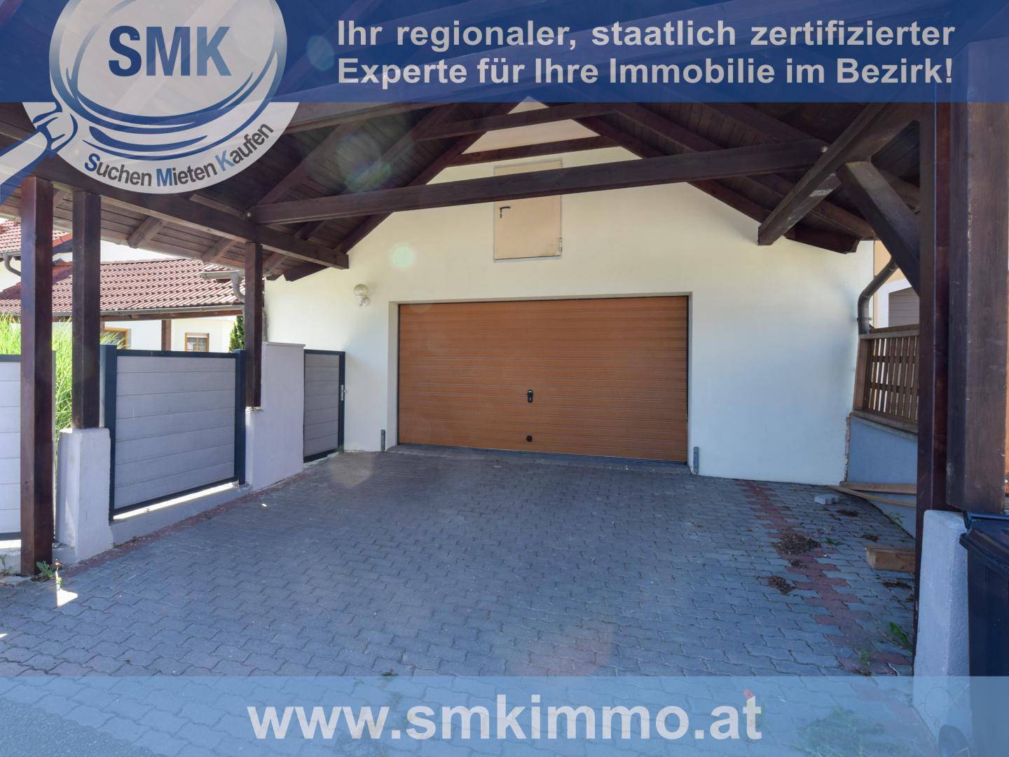 Überdachter Carport und Garage mit Holztor, gepflastertem Vorplatz und Zaun.
