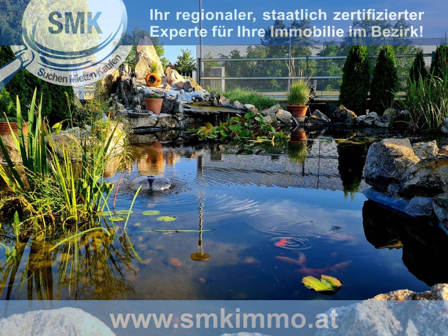 Teich mit Wasserfontäne, Seerosen und Goldfischen in einem naturnahen Garten.
