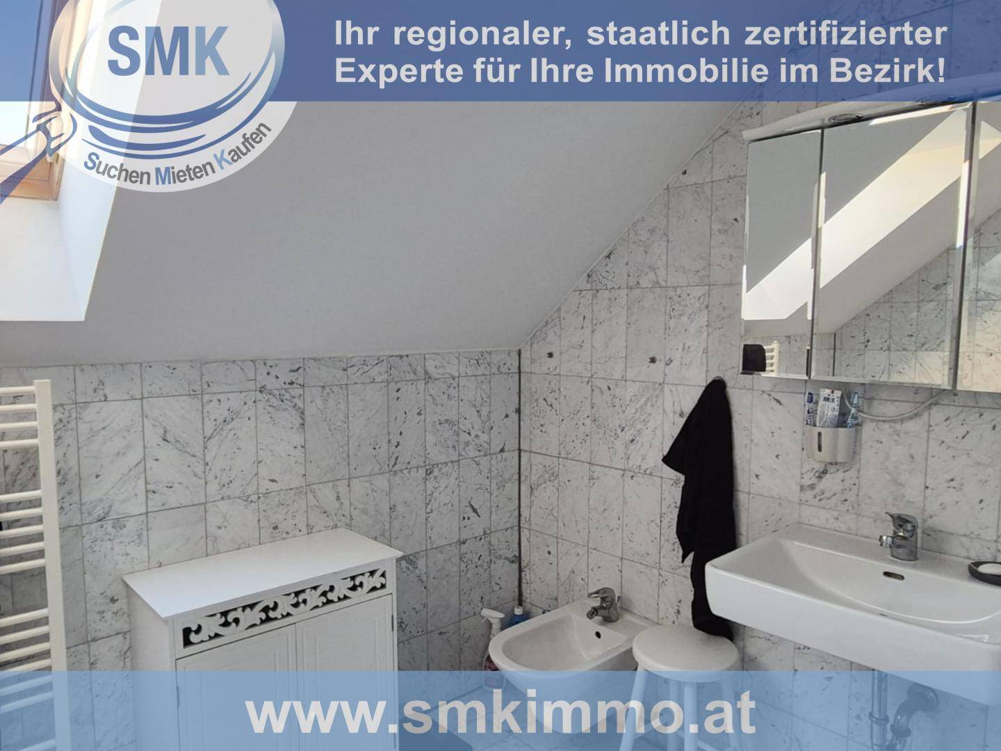 Gefliestes Badezimmer im Dachgeschoss mit Dachfenster, Waschbecken, Bidet und Spiegelschrank.
