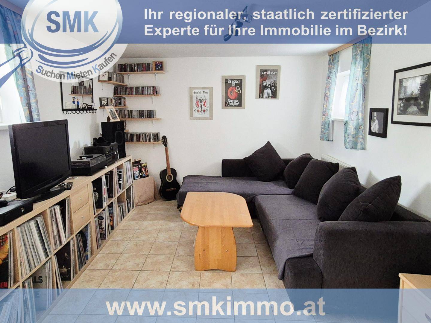 Gemütlicher Wohnbereich im Untergeschoss mit großem Sofa, Fliesenboden und vielen CDs.