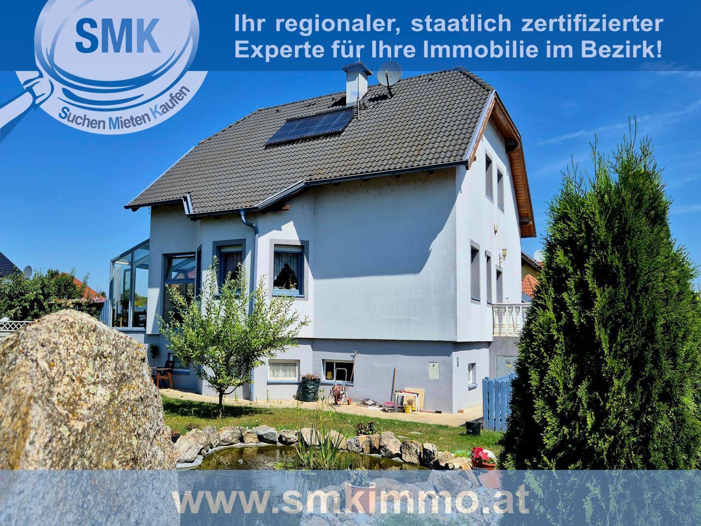 Freistehendes Einfamilienhaus mit Garten, Teich und Photovoltaikanlage auf dem Dach.