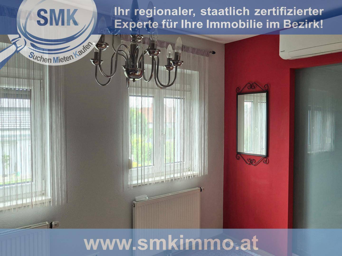 Raum mit roter Akzentwand, Fenster und Kronleuchter, möglicherweise ein Flur oder kleines Zimmer.