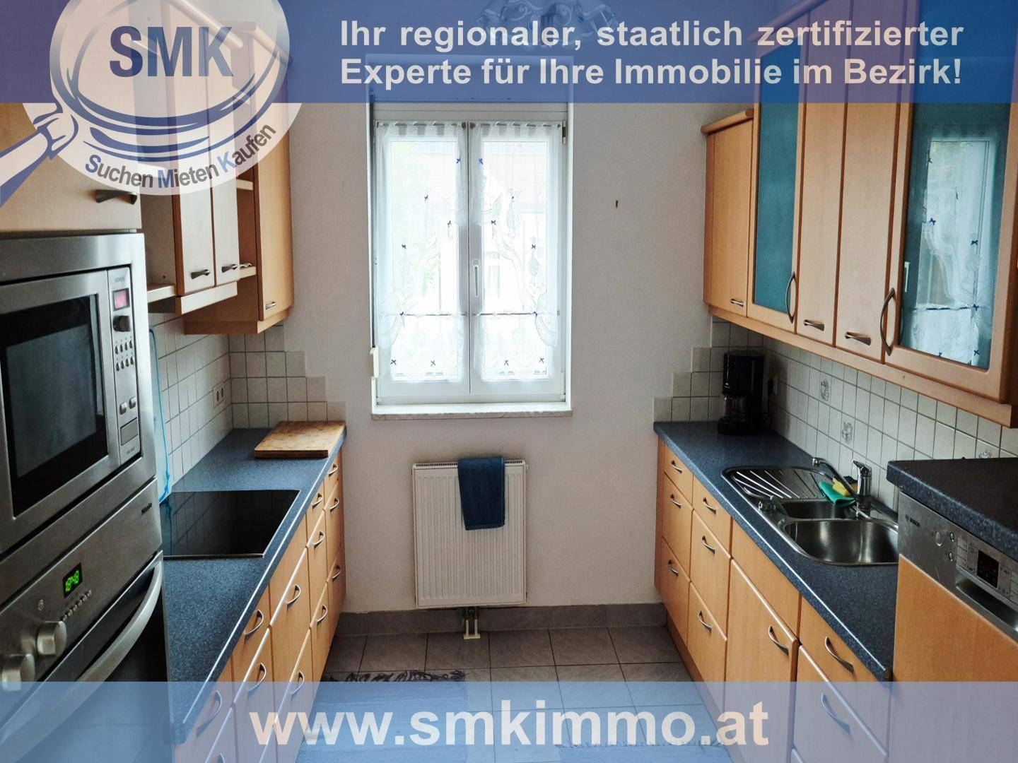 Funktionale Küche mit Holzschränken, blauen Arbeitsplatten und integrierten Geräten.