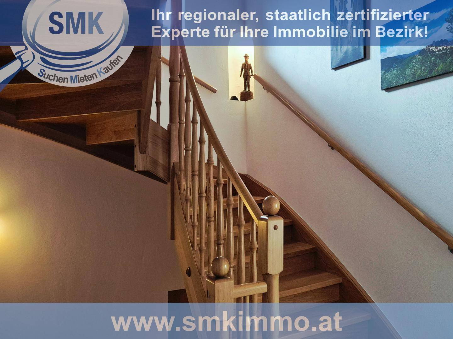 Holztreppe mit Geländer führt in die oberen Stockwerke des Hauses.