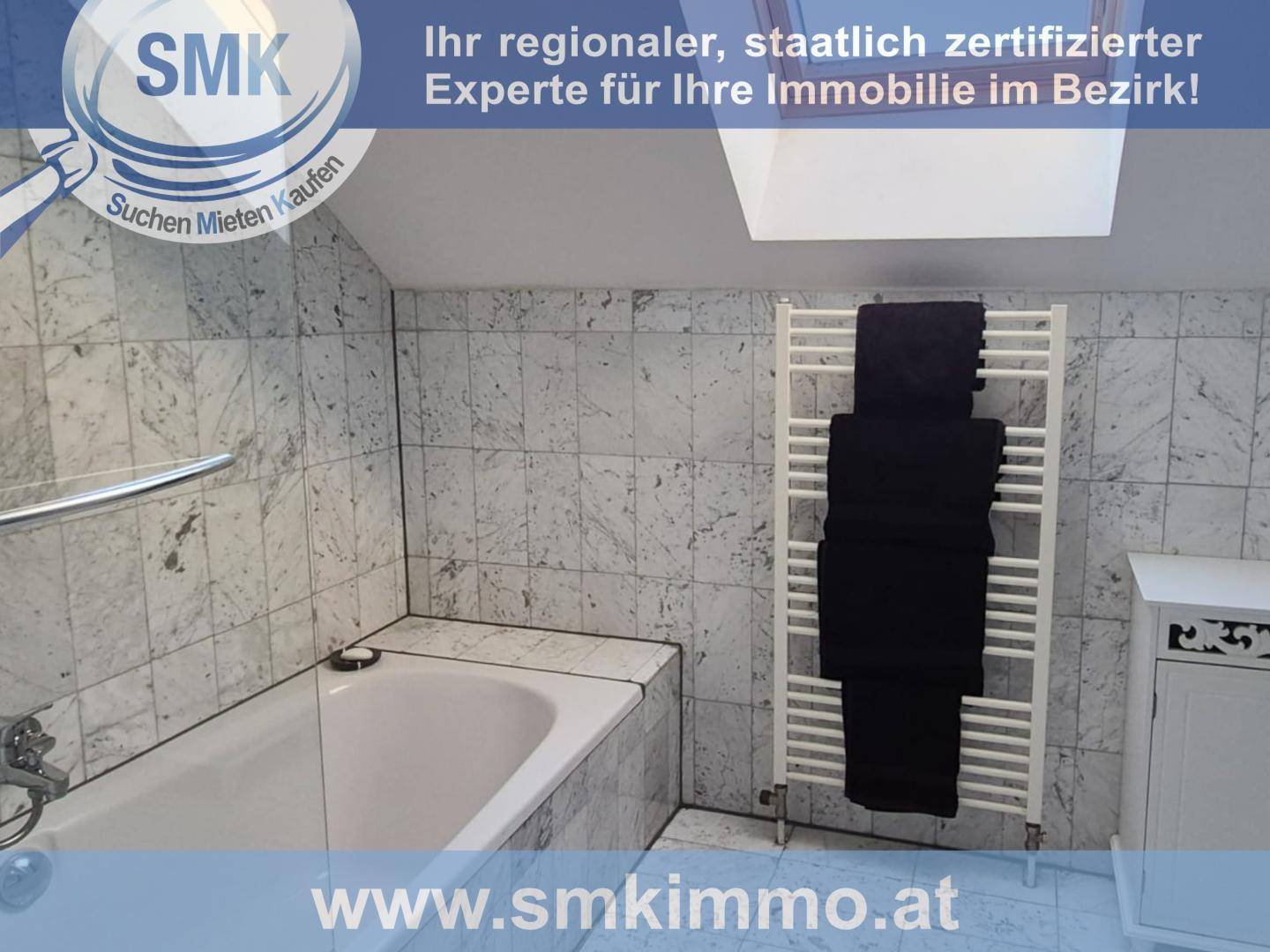 Badezimmer mit Badewanne, Fliesen, Dachfenster und beheiztem Handtuchhalter.