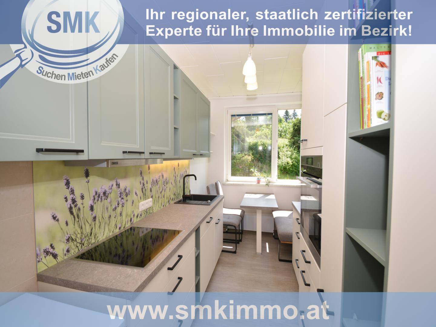 Moderne Küche mit hellgrauen Schränken, Induktionskochfeld und kleinem Essbereich am Fenster.