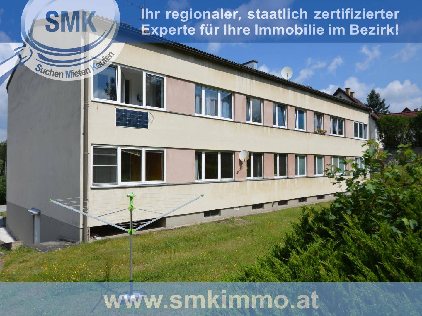 Mehrstöckiges Wohngebäude mit mehreren Fenstern und einer Wäscheleine im Vordergrund.