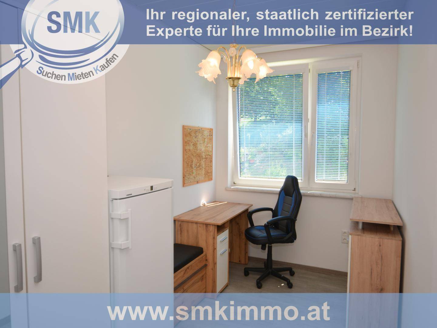 Kleines Arbeitszimmer mit Schreibtisch, Bürostuhl und Kühlschrank, gut beleuchtet durch ein Fenster.