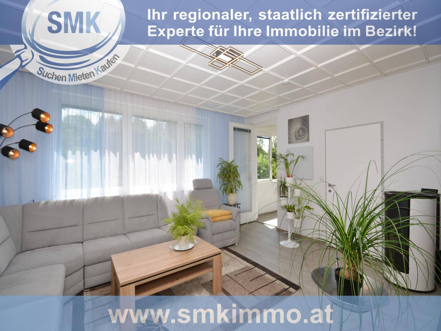 Helles Wohnzimmer mit gemütlichem Ecksofa, Holztisch und großen Fenstern mit blauen Vorhängen.